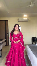 Woman in a pink traditional outfit standing in a room with an air conditioner on the wall.